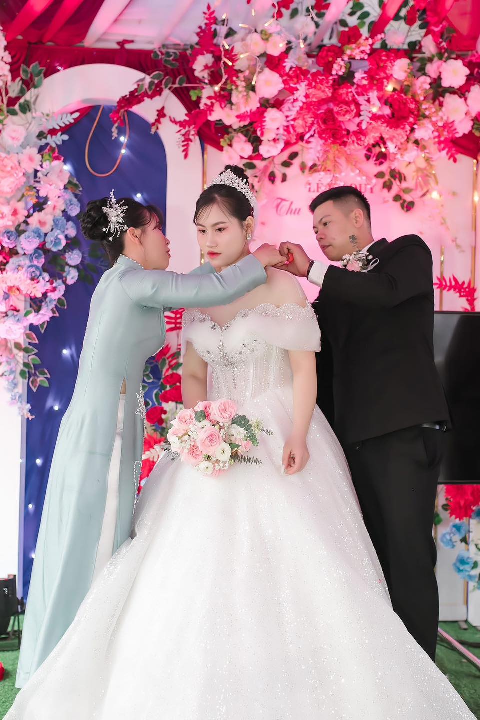 Có thể là hình ảnh về 2 người, hoa cát tường, đám cưới, cái bục và văn bản